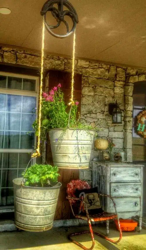 De vieux seaux suspendus transformés en pots de fleurs